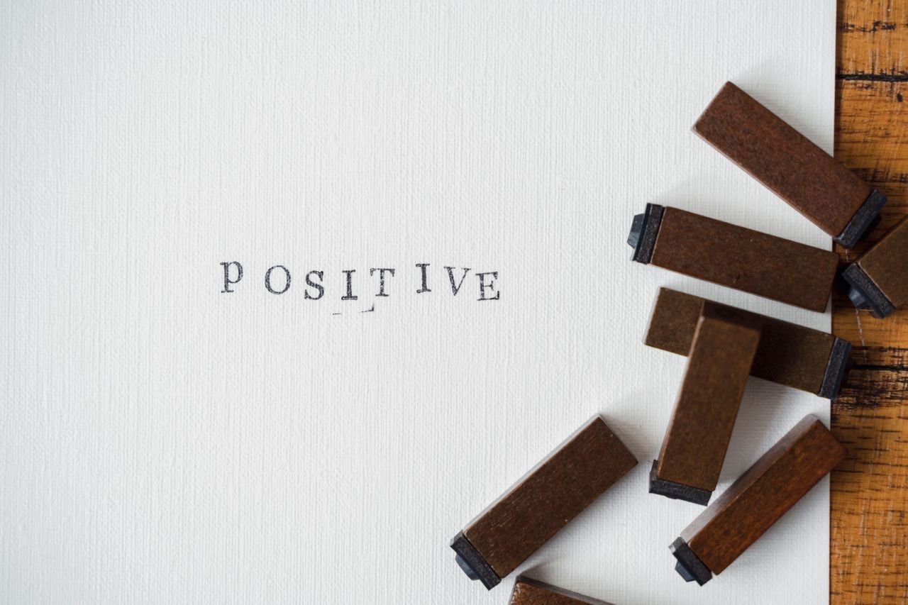 Close-up of Positive word created with vintage wooden letter stamps on textured paper.